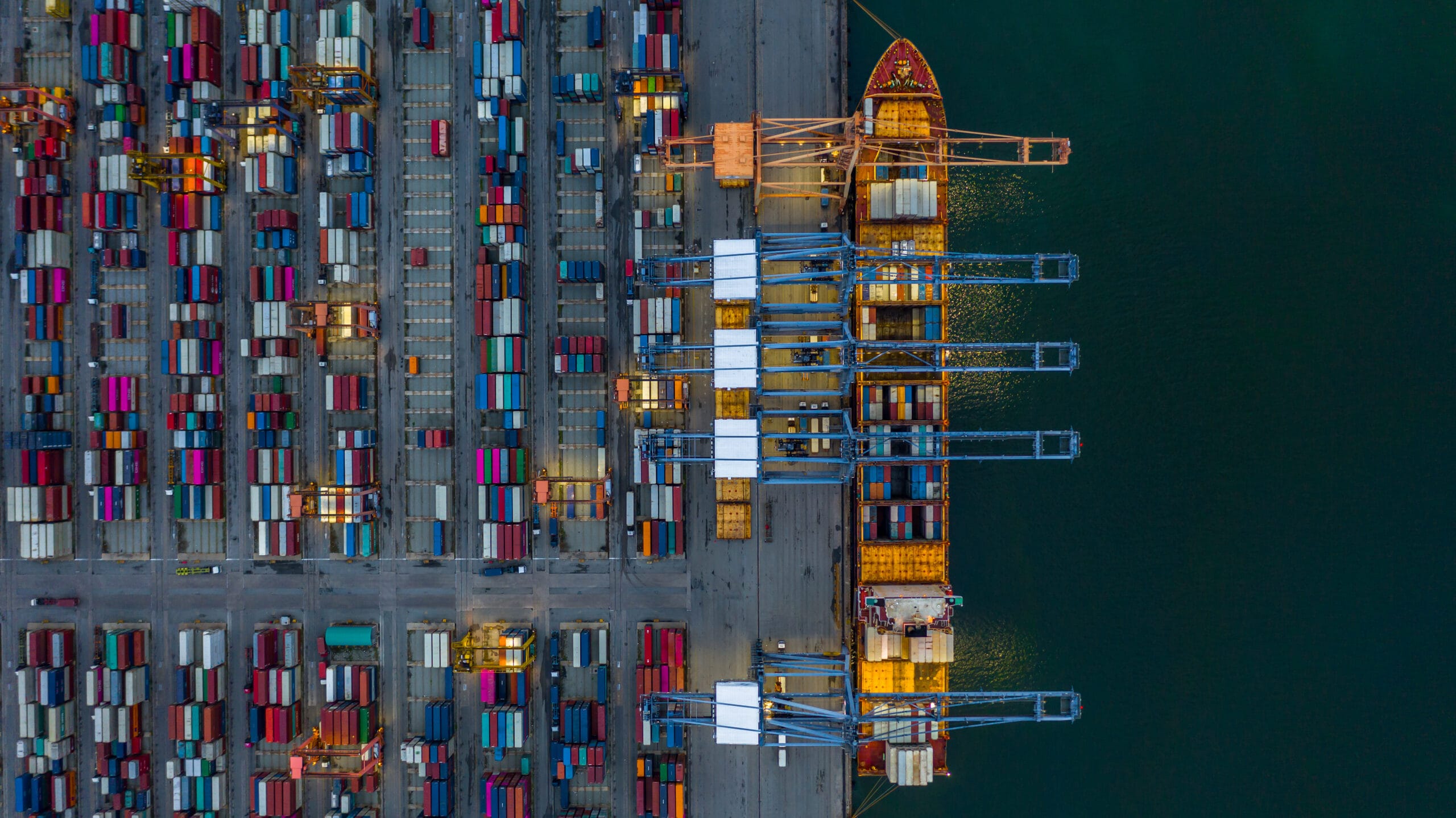 Aerial view container ship loading at night in industrial port,
