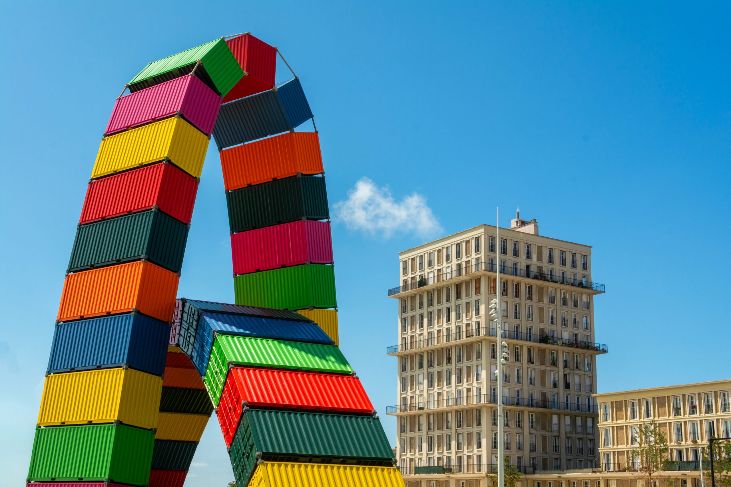 Vibrant shipping container sculpture against the Le Havre skyline on a clear day.